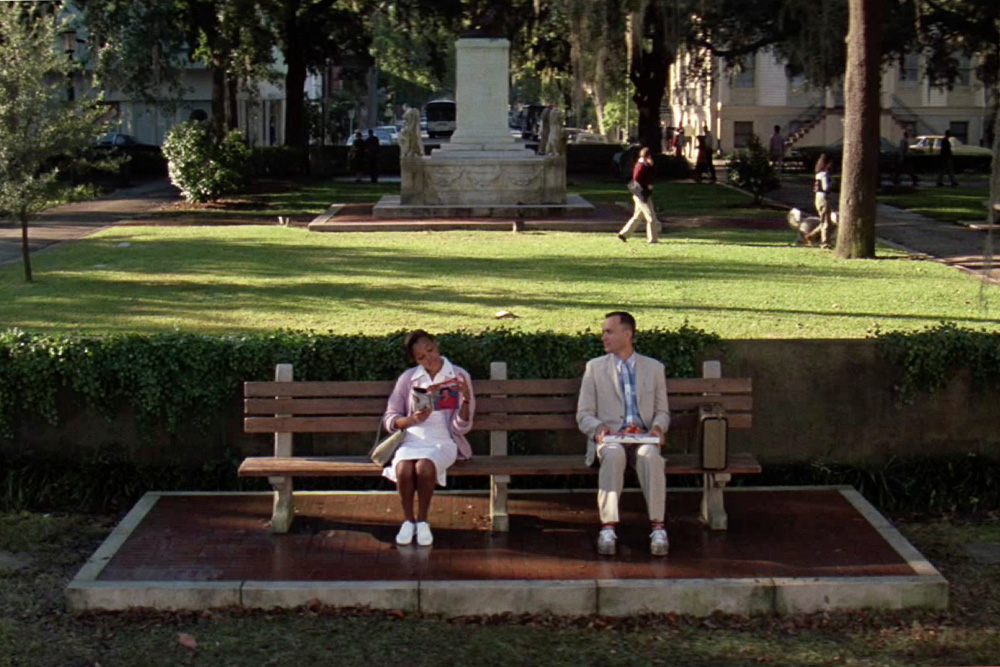 Forrest Gump sits aside a woman in his famous "life is like a box of chocolates quote" to suggest the visual nature of his compelling character beside the movie's logline