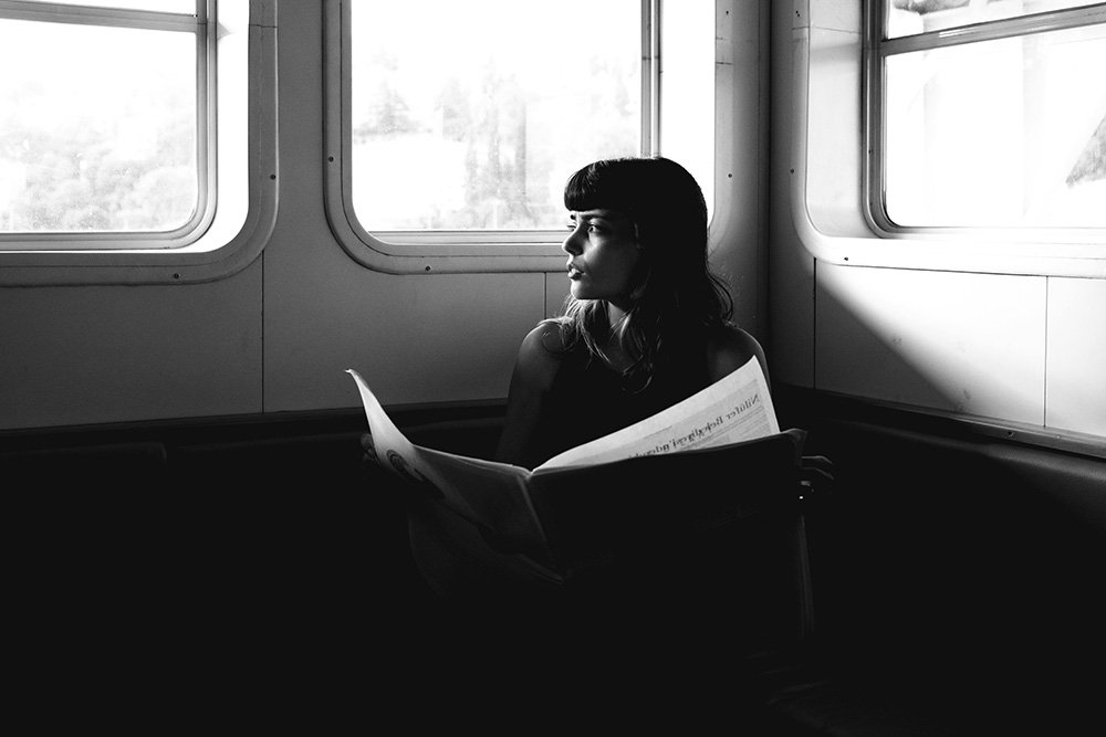 A woman looks out into the sun while reading to suggest that she has a clear sense of some bigger picture while revising vs. editing