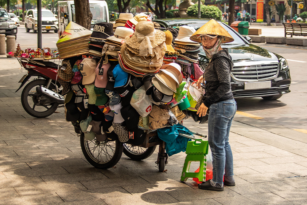 A street vendor stands beside a lot of hats to signify a writer who has lost sight of the story in too many hats as a screenwriter