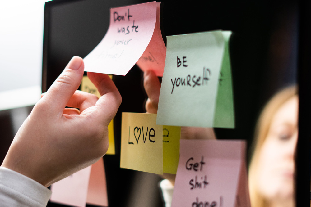 A mirror adorned with sticky note affirmations to suggest that certain words are used to open the writer up to themselves and the world around them