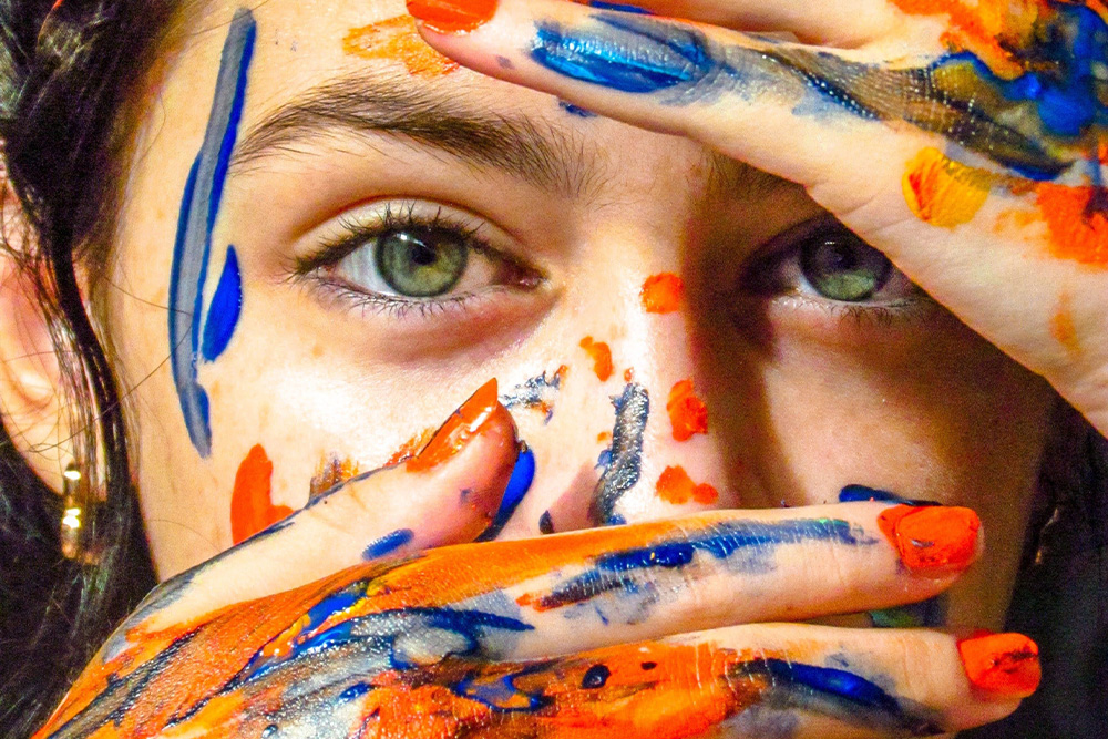 A woman covered in streaks of paint is a message for how to adapt a book into a screenplay, suggesting that movies require a visual palette of colors in order to portray interior worlds