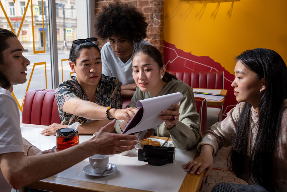 A group of people crowd around a screenplay on a set to suggest how one might consider the needs of an audience in how to adapt a book into a screenplay