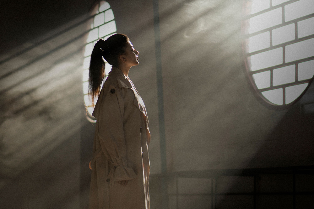 Hazy setting with creative lighting, a woman looking into the light — cinematic setting is an example of how to adapt a book into a screenplay