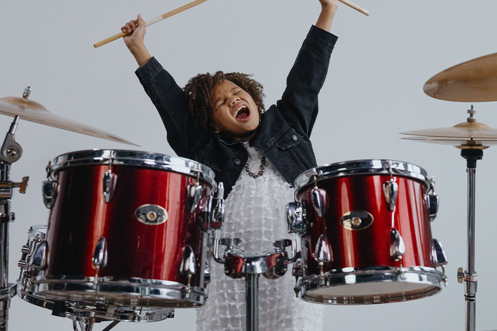 A child with drumsticks and a yawn on her face is a clue that asking "what is rhythm?" will help a writer tap into the emotions of their audience effectively