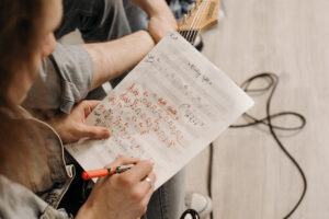 Someone sits by a marked up sheet of music to suggest what is rhythm in writing