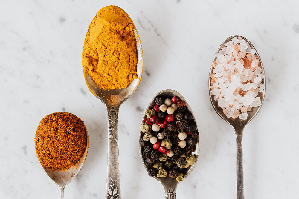 Four types of seasonings on a plain white background suggests healthy ingredients of a critique circle that have their time and place in different foods
