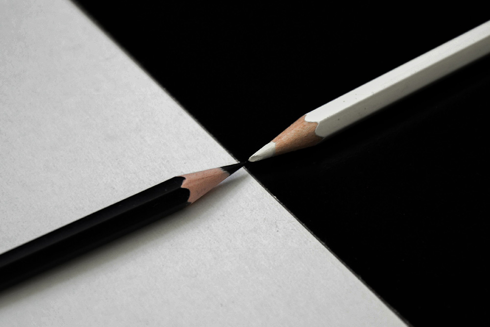 Black pencil on white background and white pencil on black background suggest contrast and a meeting place for all modes of developmental editing in a suggested line