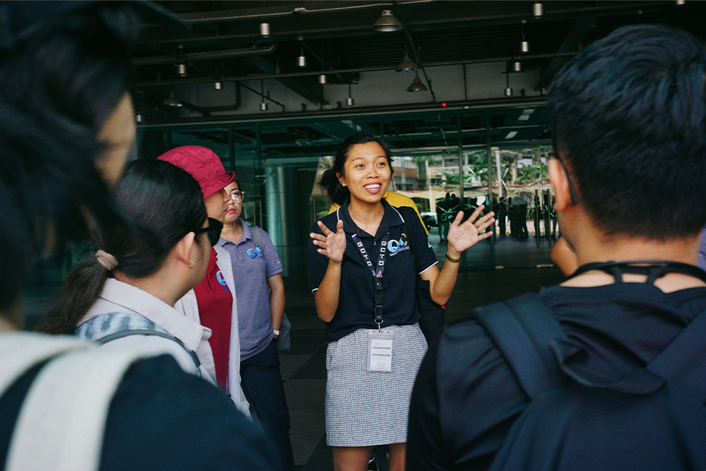 A travel guide in the center of frame telling everyone else about something passionately as a visual metaphor for how writers can use dialogue tags in their storytelling