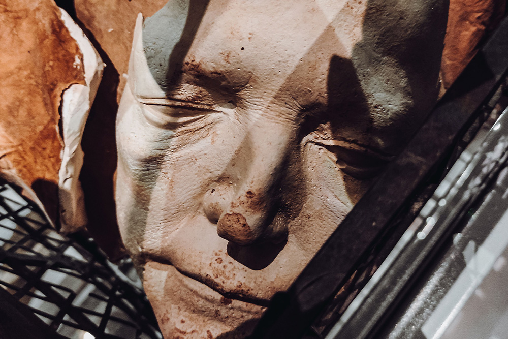 A face appears to be a shattered ceramic in a pile of materials to suggest how to compile the hero archetype
