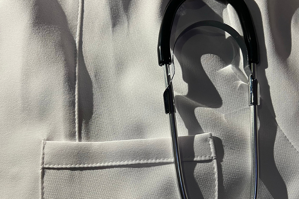 Stethoscope placed above breast pocket in dramatic lighting as a visual parallel for Dr. Kalanathi's example on how to start a memoir