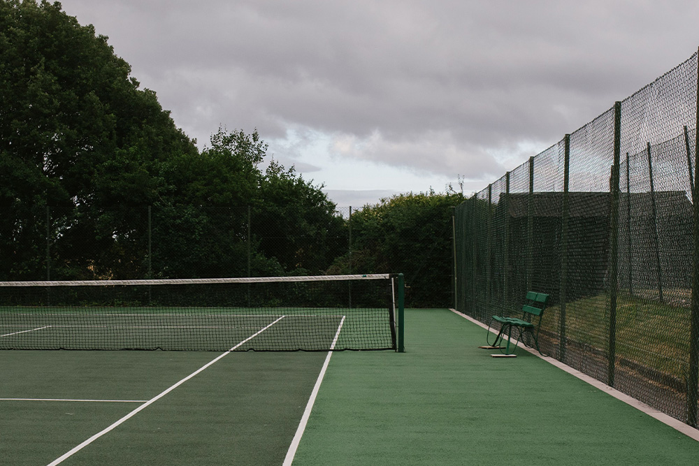 Tennis court with a lower third bench placed against a cool overcast day suggests freedom and darkness behind the words of Andre Agassi on how to start a memoir