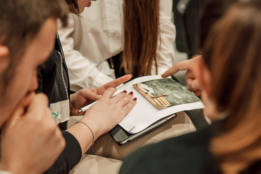 A group of people gathered around a clipboard suggesting what makes a good peer learning group