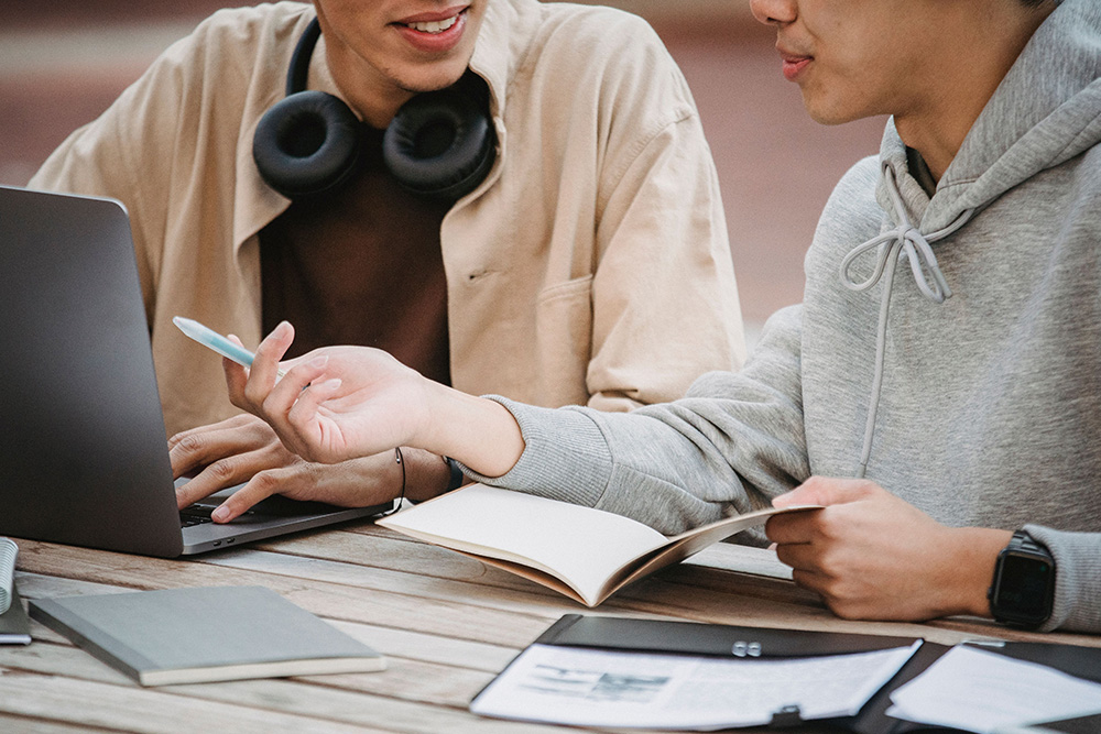Two people sit beside a laptop to suggest how to give better feedback in peer learning