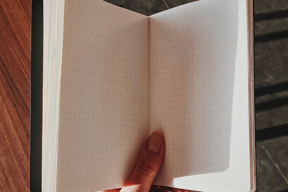 An empty notebook in shade suggests that prompts will make it easier to bring your light into writing journals