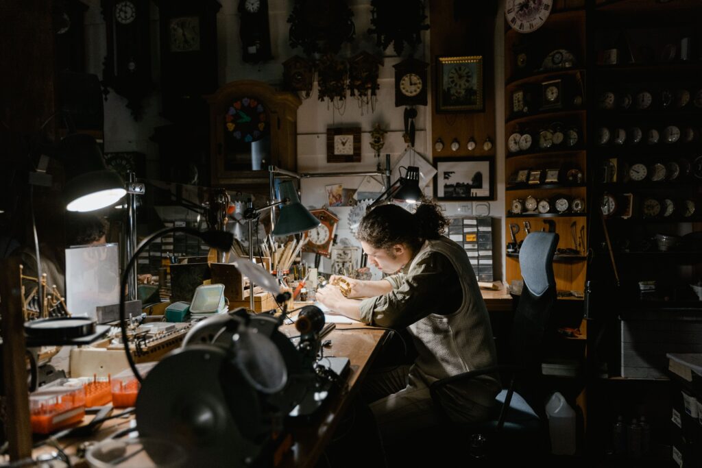 A watchmaker diligently works under a single light to suggest that you must show up as often as you can
