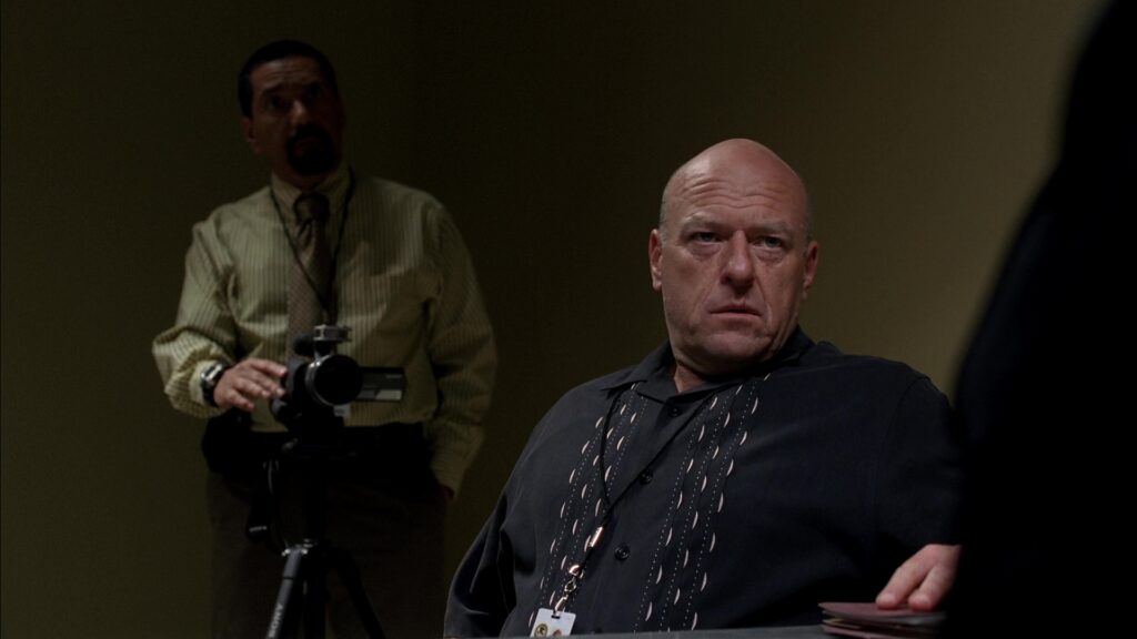 Hank from Breaking Bad with a funny face to suggest a seriousness to his character in antagonist examples