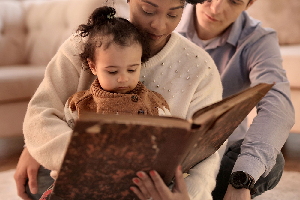 A mother taking her daughter through a photo album to suggest the real story of the caregiver archetype