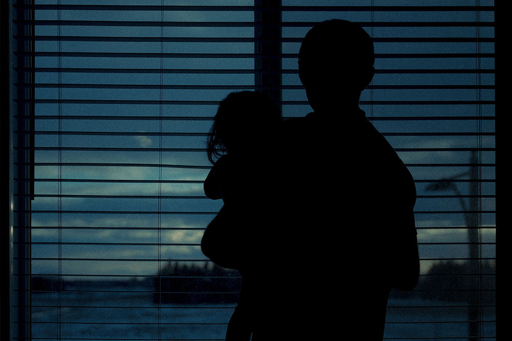 A parent and child looking through a window in silhouette to suggest how the caregiver archetype has a duality embedded in their nature