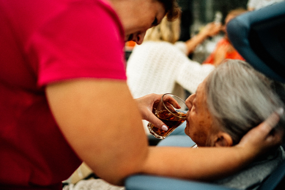 A woman being given a drink by a nurse to suggest the classical example of the caregiver archetype
