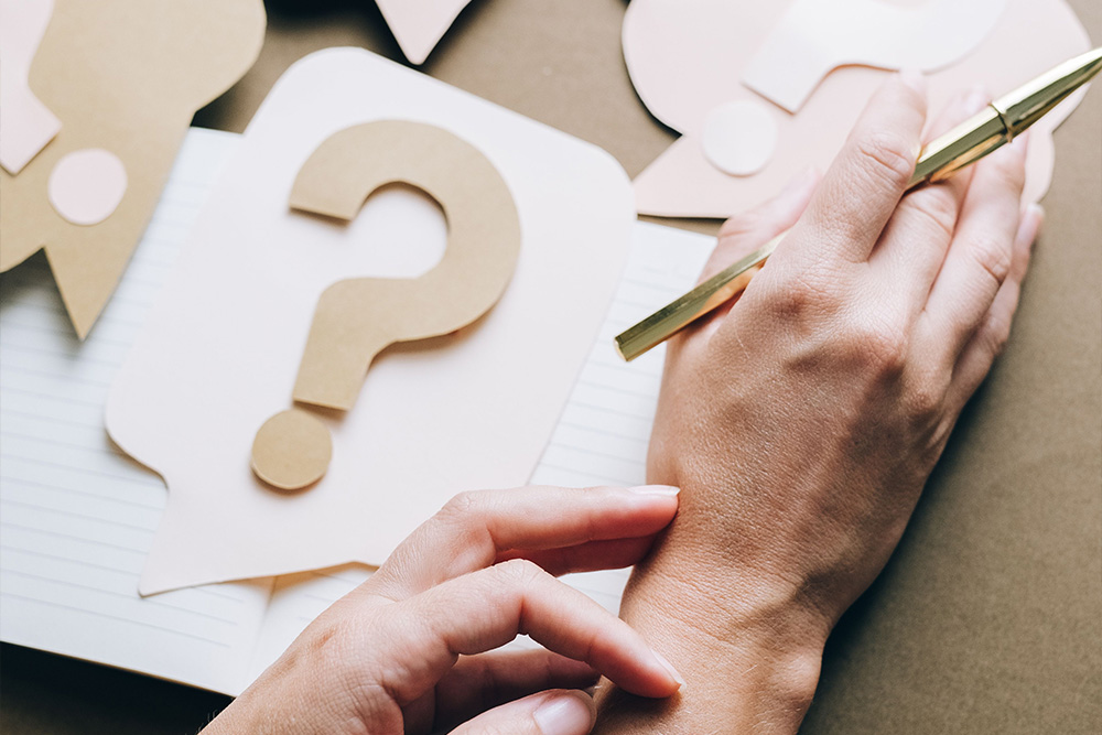 A notebook covered with question marks to suggest that critical feedback comes in many shapes and forms on the page