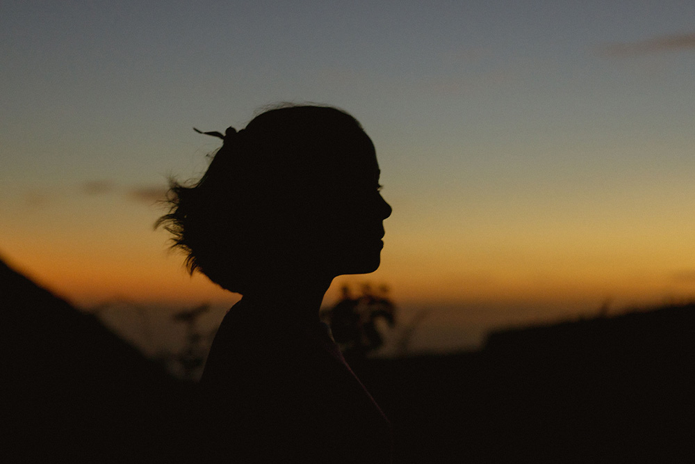 A woman in silhouette against a sunset suggests a glory to writing a concept where the main character is the villain