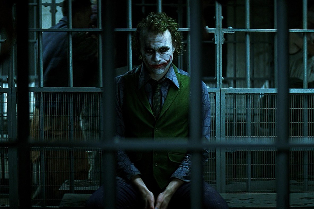 Image of the Joker brooding antagonistically to suggest the character of the trickster archetype is allowed to be violent to carry out this semblance of truth