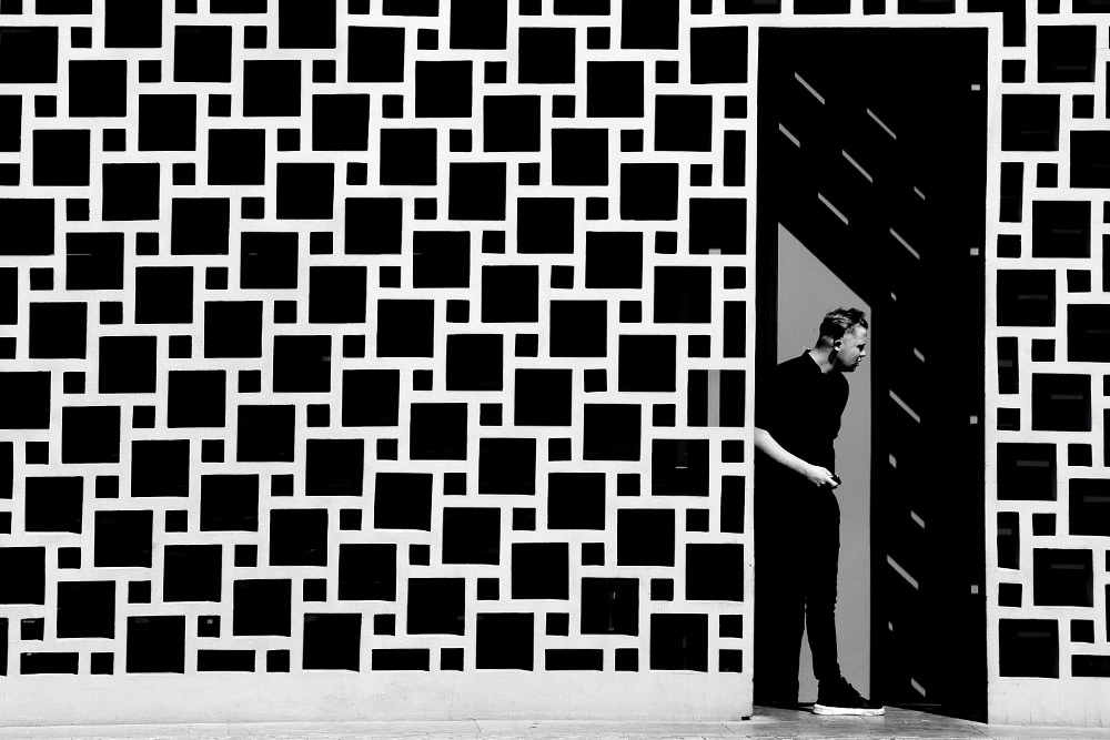 A man in a doorway with a repeated pattern outside it suggests the reader's approach to a work equipped with the effort of a literary devices list