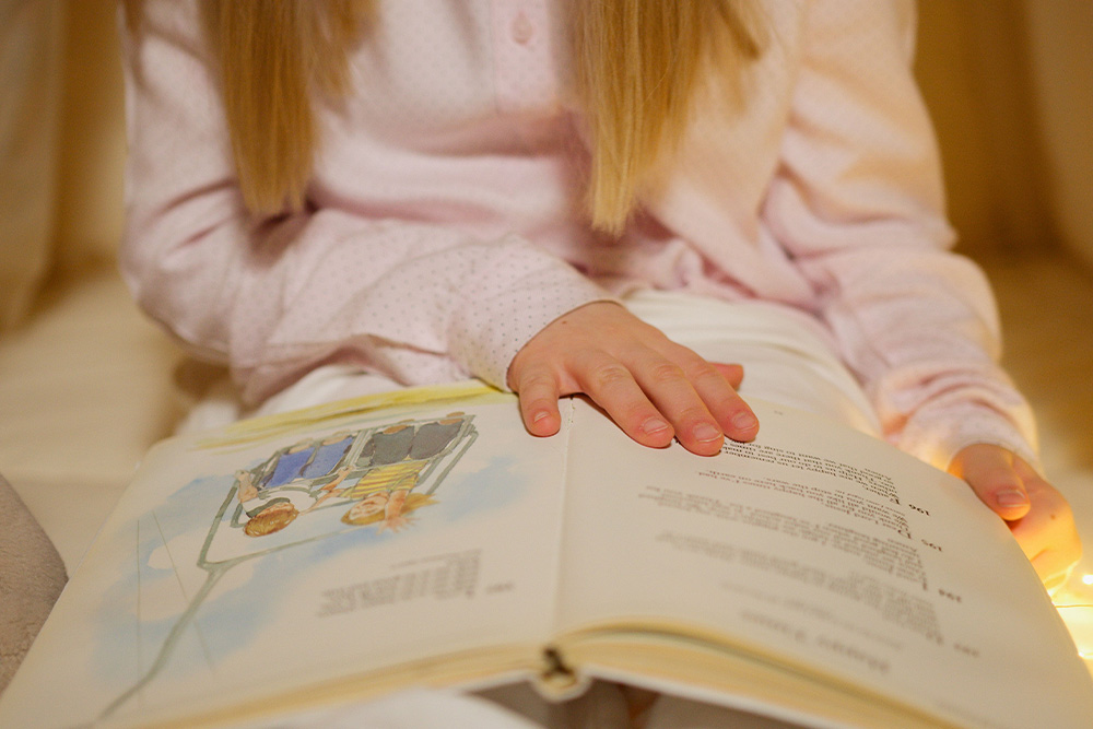 A kid with a story book suggests that narrative devices allow a story to bring a reader in deeply and in lightness with a literary devices list