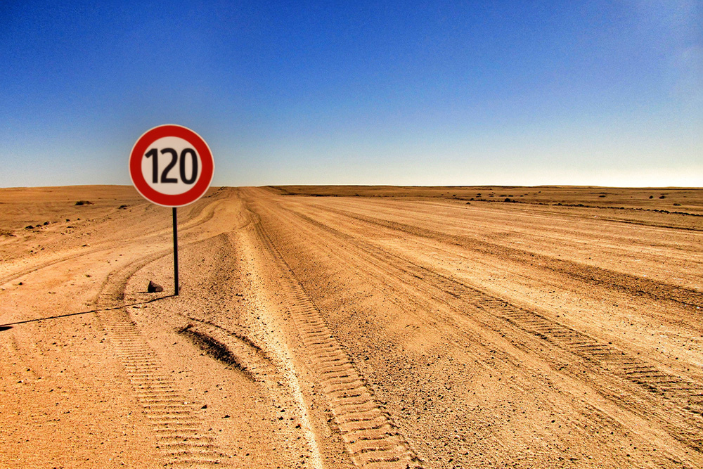 An empty dirt road with a speed limit for 120 km/h posted nearby to suggest the wide open road for a writer equipped well with a literary devices list