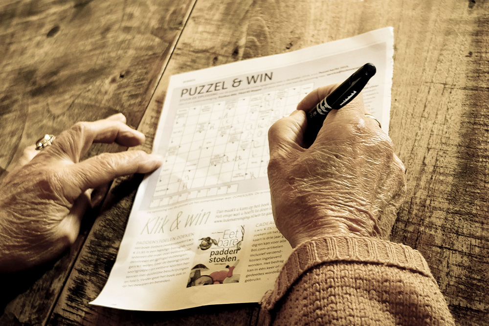 A crossword being done by an elderly woman suggests a peace, tranquility, and gameishness to finding book title ideas