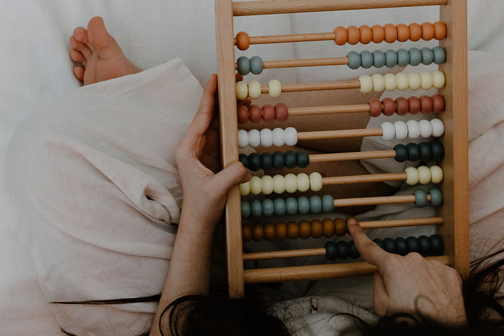 A woman arranging an abacus helps visualize variables that may not immediately explain how much do writers make