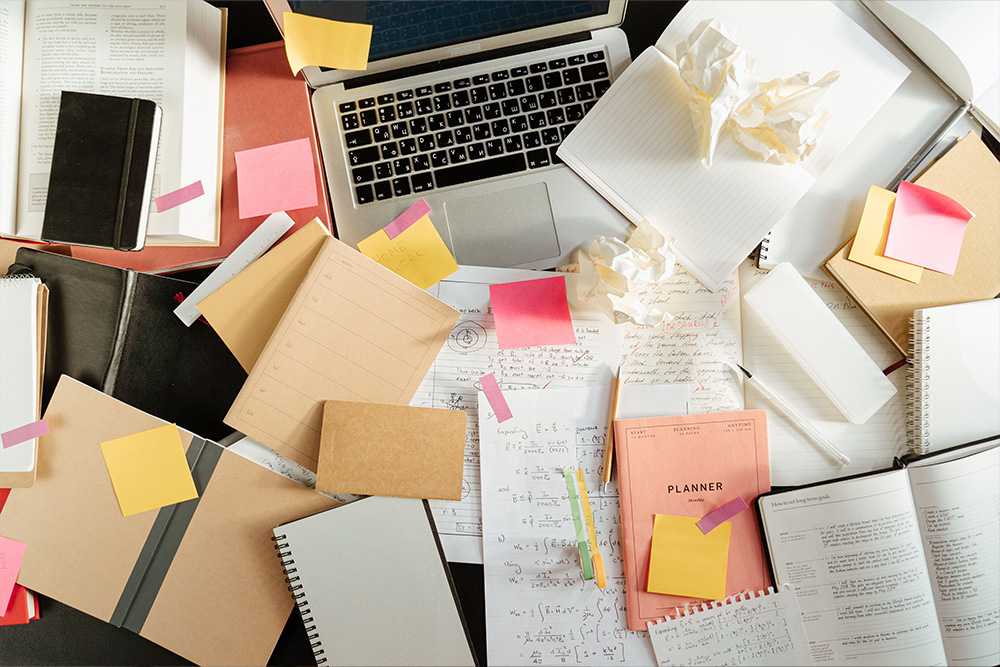 Notes scattered on a desk across a laptop to suggest messiness in how different writers make different amounts to answer the question how much do writers make