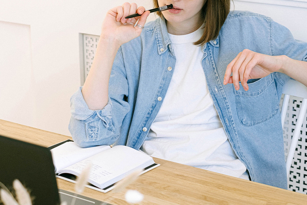A woman with a pen in her mouth seems to be pensive and thinking to suggest that writers spend time thinking about writing rules