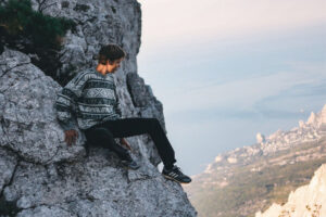 A man at the edge of a cliff looking out over ostensibly a big drop below