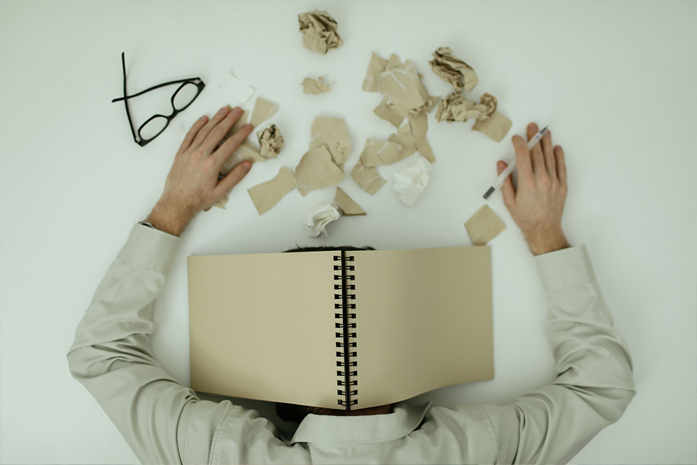 A faceless character with their head down in a book to suggest dangers of first-person omniscient