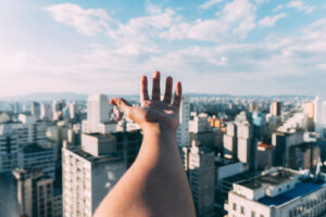 A first person omniscient perspective image of a hand reaching over a city