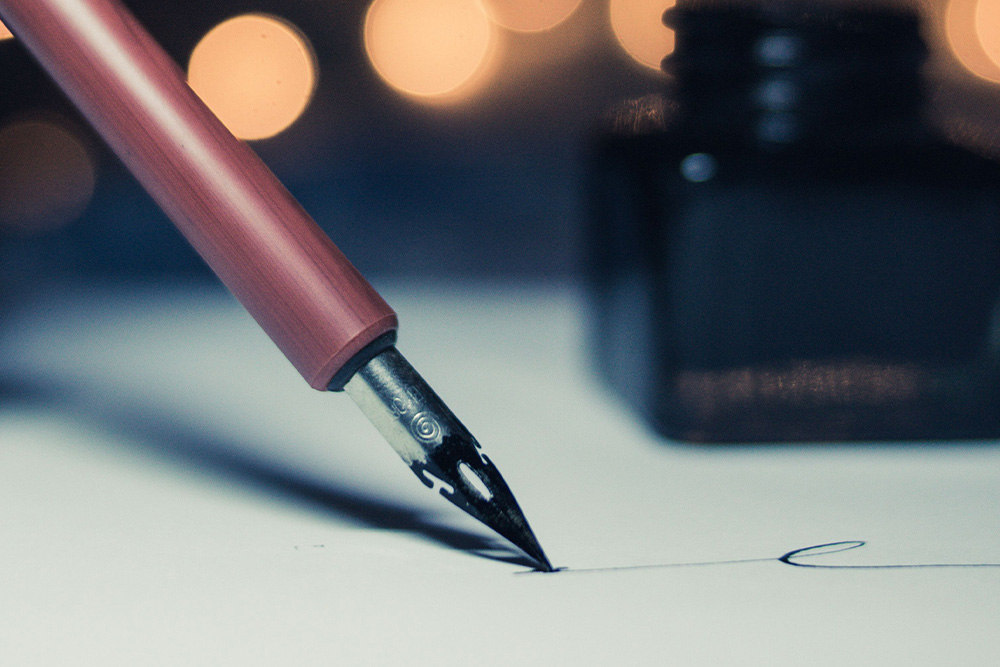 A pen writing in fancy type to suggest how to get a book deal with a quality query letter