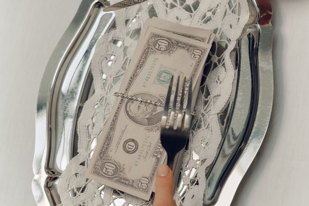 A fork cutting up a plate with money on it suggesting hybrid publishing saves you from this pitfall of traditional publishing methods
