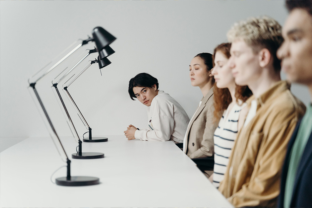 A person looking at a series of others who are absorbed elsewhere  to suggest how literary fiction readers expect a level of inherited intertextuality