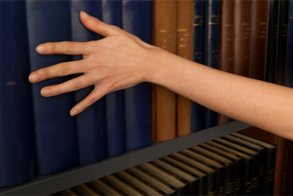 A woman's hand running her fingers over some books to suggest a softness to literary fiction