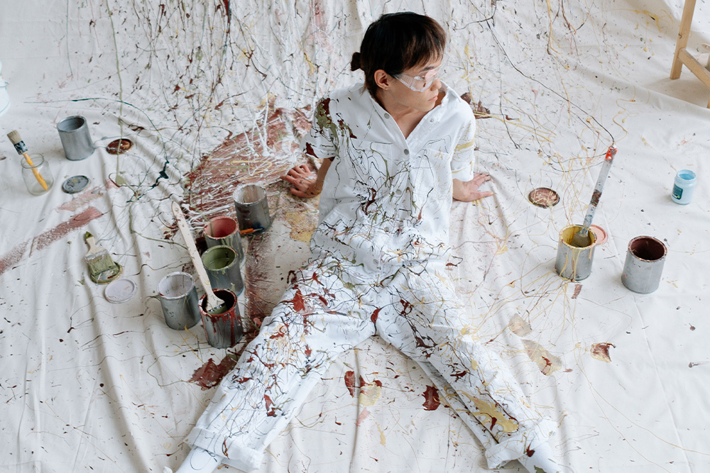 Someone in a messy painting studio environment to suggest how reverse outlining helps you clean up