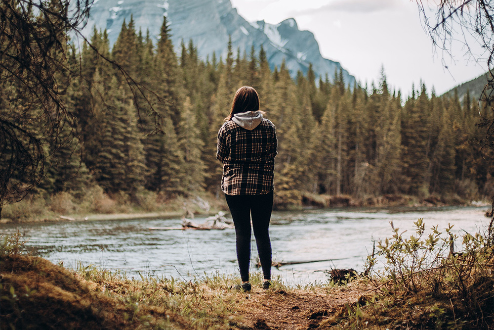 A woman before a serene lake to suggest seeker archetype vs. the outside world