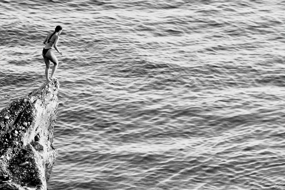 A woman on a cliff preparing to jump to convey suspense 