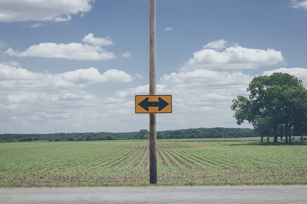 A sign in the middle of a long road suggests visually how a writer might forget which way is the way forward without writing motivation