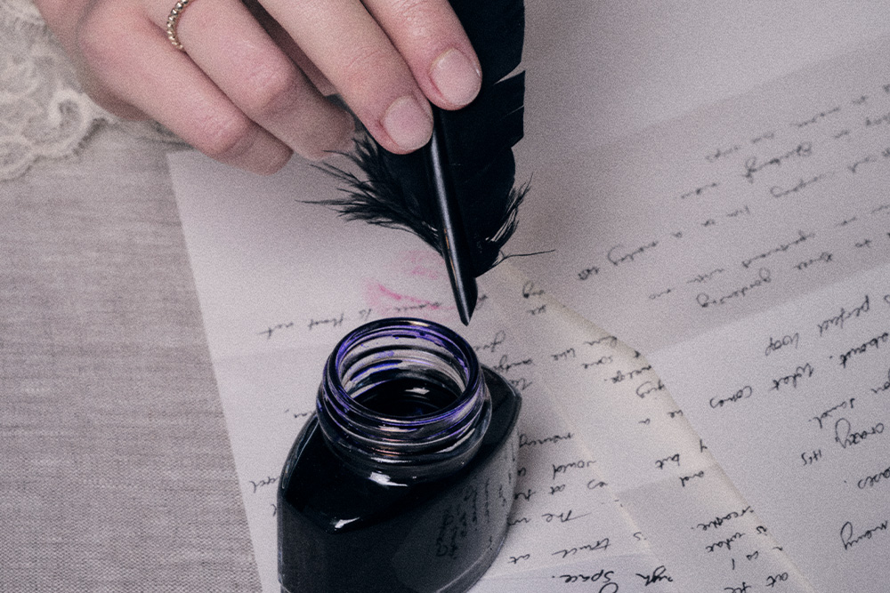 A hand with a feather quill pen being dipped into ink alluding to formalism in writing techniques