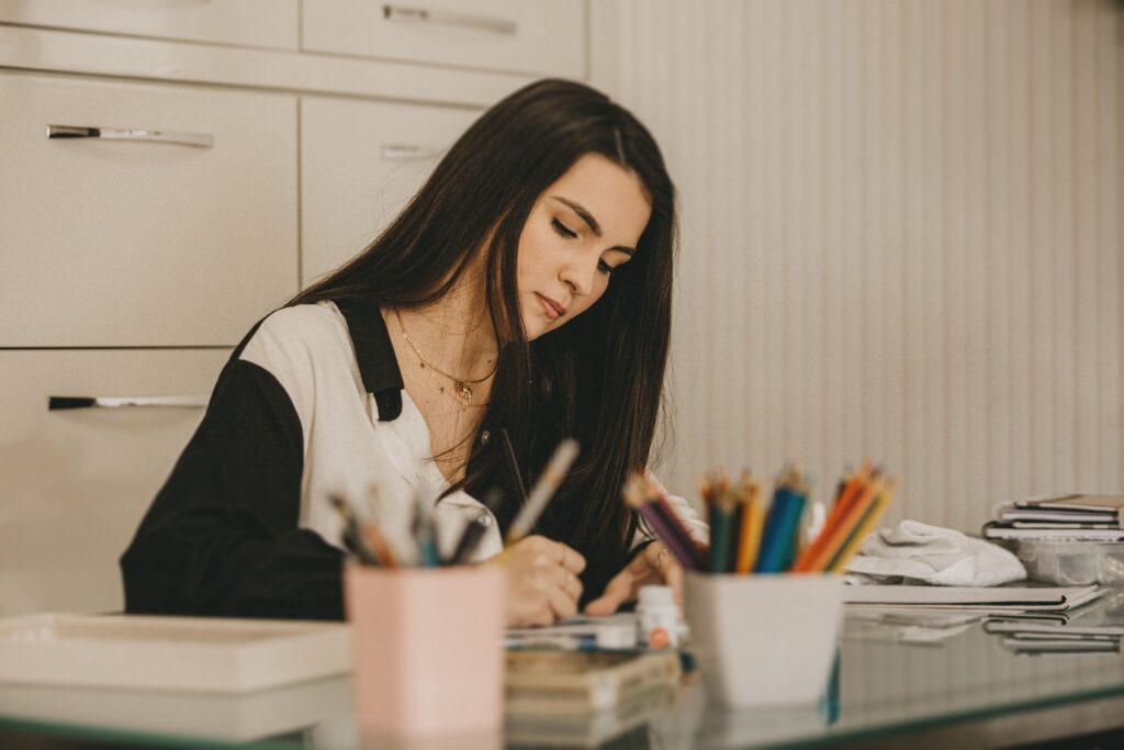 A woman writing on a pad of paper deep in thought to suggest difficulties in writing bad character traits