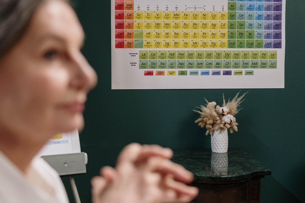 A periodic table of elements next to a woman's face to suggest thinking about the elements of fiction