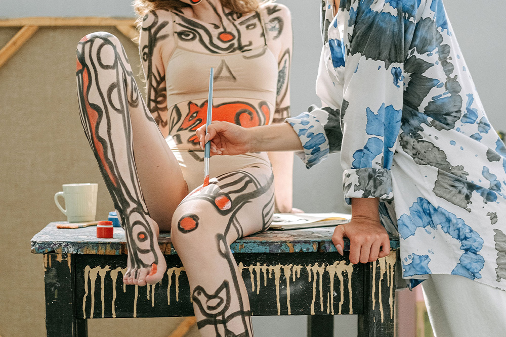 A painter skipping the canvas and painting directly onto a human body as an example of how some writers work with character sketch