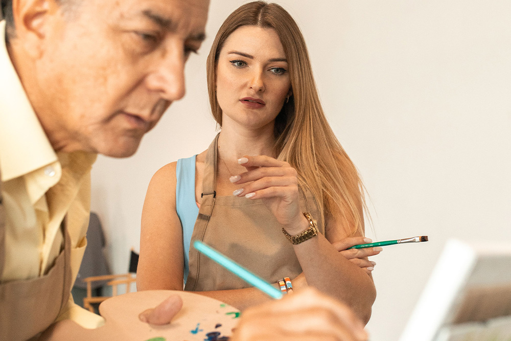 A woman observing someone paint with a look of concern, he's ostensibly making a mistake in the character sketch