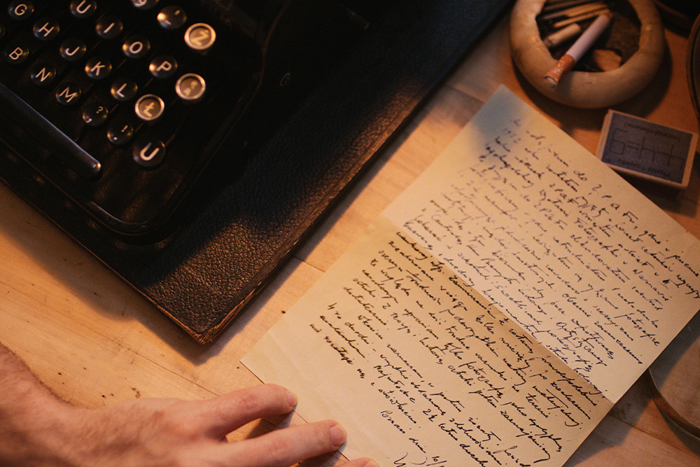 A high quality paper with fine handwriting on it beside a typewriter to suggest formal diction
